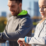 Man and woman walking outside looking at their smart watch